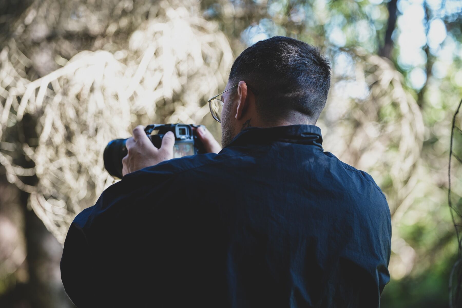 Felipe filming in a forest, seen from behind