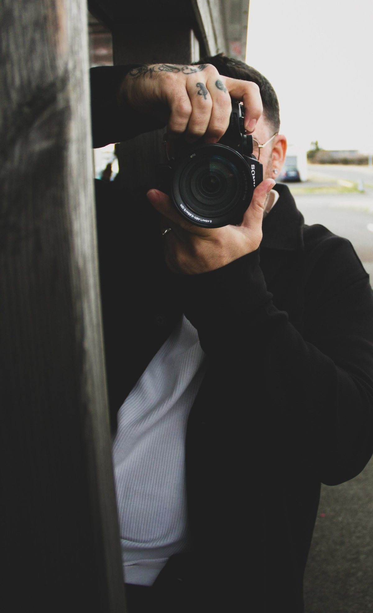 Felipe taking a photo from behind a wooden wall